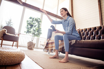 Full size photo of unhappy upset young woman hold hand joystick play game sit sofa indoors inside...