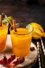 Pumpkin cocktail with autumn decor on wooden table.