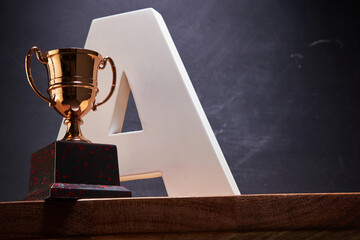capital letter A and wining trophy against blackboard