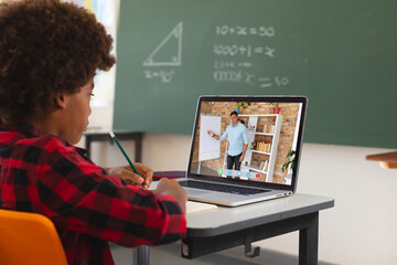 African american boy using laptop for video call, with male teacher on screen - Powered by Adobe