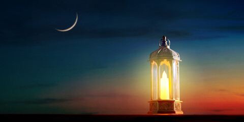 Muslim holy month Ramadan Kareem - Ornamental Arabic lantern with burning candle glowing with...