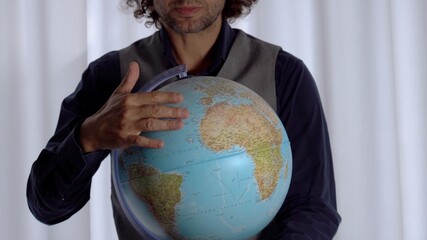 40-year-old businessman in smart working holds a globe model  in his hand to decide the travel destination with the end of quarantine due to Covid-19 Coronavirus