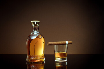 close up view of cigar, bottle of cognac and a glass aside on color back. 