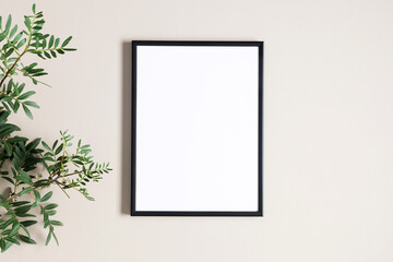 Empty photo frame and branch with green leaves on beige background. Flat lay, top view, copy space