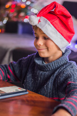 a happy child in Santa Claus's hat thinks about a gift and plaing