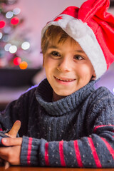 a happy child in Santa Claus's hat thinks about a gift and plaing
