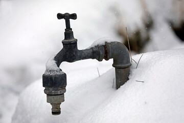 Faucet with frozen water, garden in winter with snow and ice.