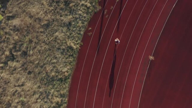 man jogging on sports field in the evening with long shadows on ground