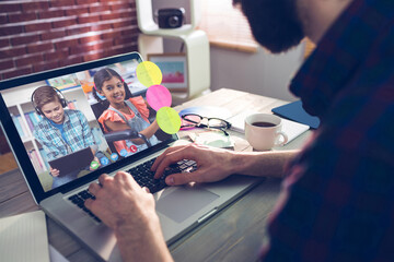 Fototapeta premium Caucasian man using laptop for video call, with diverse elementary school pupils on screen