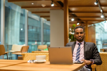 Young African businessman in coffee shop using laptop computer