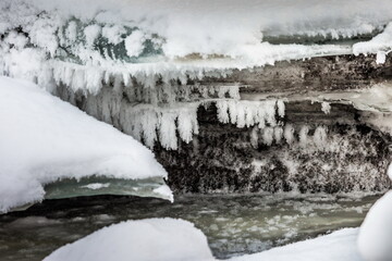 Icicles and frost on a snow-covered frozen river