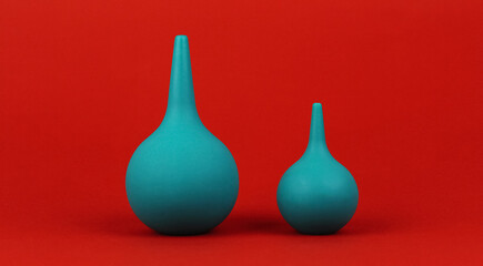 Two green rubber medical pears of different sizes on a red background