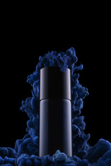 Splash of blue ink in water with metal bottle isolated on black background. Blue smoke with deodorant spray on black background with empty space on top.