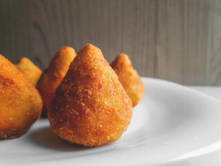 Brazilian coxinha on white plate and wooden background and with space for text and with