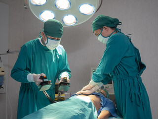Doctors give resuscitation to a male patient in the operation room, rescue safe life patients with automated external defibrillator emergency moment concept