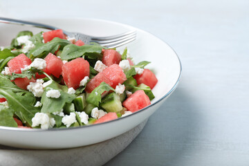 Delicious salad with watermelon, cucumber, arugula and feta cheese on white table, closeup. Space for text