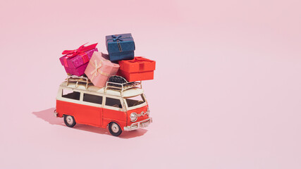 A Christmas arrangement made of red van and gifts on a pastel pink background. Minimal New Year and delivery concept. Christmas tree and Christmas time inspiration.