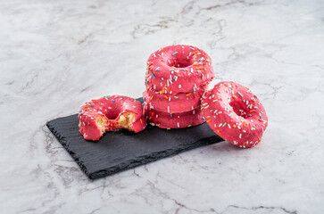 donuts de azucar y colorines rosas encima de una mesa de marmol