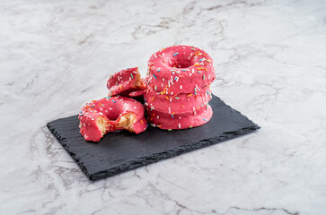 donuts de azucar y colorines rosas encima de una mesa de marmol - obrazy, fototapety, plakaty