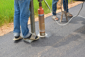 A technician is drilling a road to measure the thickness of the road.