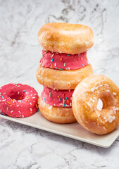 donuts de azucar y colorines rosas encima de una mesa de marmol - obrazy, fototapety, plakaty