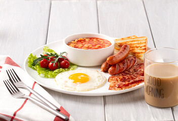 Traditional Full English breakfast, on a white background, fried eggs with fried bacon, sausages, white beans ,cherry tomatoes, horizontal, no people,