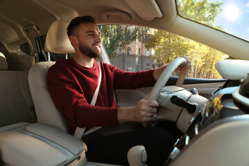 Handsome young driver sitting in modern car