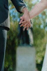 Love and relationships concept closeup of woman and man holding hands Lovers hand holding together while walking newlyweds Wedding couple bride and groom holding hands green forest background