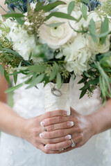 Beautiful wedding bouquet of white roses in the hands of the bride green wedding bouquet with eucalyptus in bride hands close up Ring with diamond on the bride's finger white wedding dress