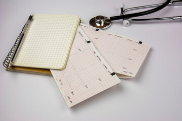 Stethoscope, notepad and electrocardiogram sheets. Cardiologist doctor's desk. Medicine and health concept