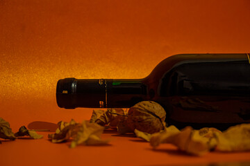 Red rose wine bottle horizontal placed on orange background with yellow leaves and walnuts. Symbol of autumn. Alcoholic drink with shiny blurred background.
Wine is an alcoholic drink made from grapes