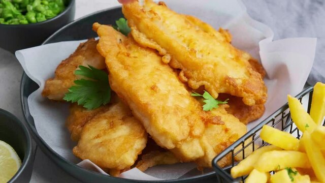 Fish and chips with green peas on gray tile background. British cuisine concept.
