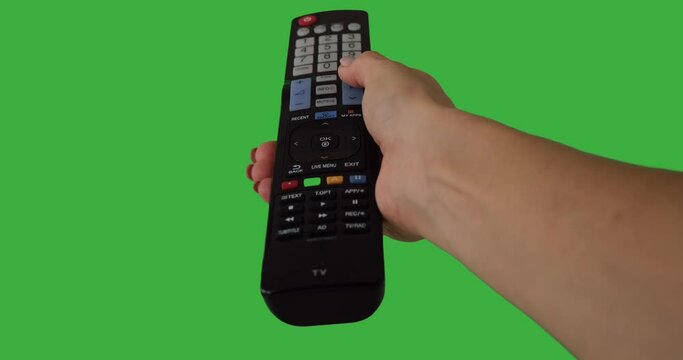 Hand pressing remote control button and changing channel over green background