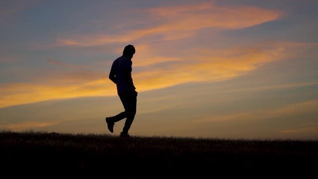 Silhouette shot of an Indian man running in front of the sun during the sunset. Man takes a jog before the sunrise. Athlete working out in the early morning and going for a morning jog. Health concept