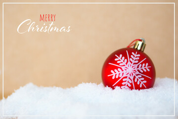 red Christmas ball with a drawn snowflake on a snowdrift on a craft background and the inscription...