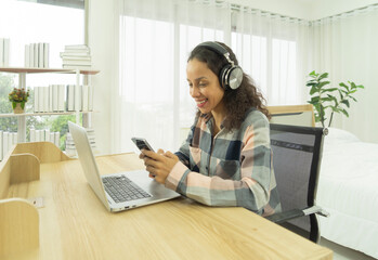 Relax happy latin young businesswoman. People typing on smartphone on social media internet and using a computer laptop notebook technology device with a bed in bedroom at home. Lifestyle