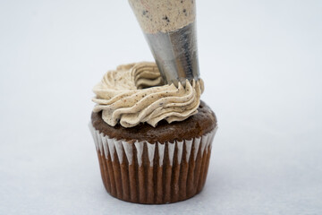 black cupcake decorated with a piping bag white cream