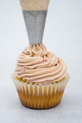vanilla cupcake decorated with piping bag pink cream 