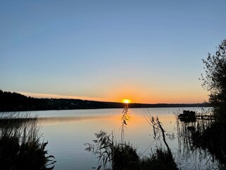 Evening lake from the shore and sunset over the horizon. Evening on the pond