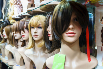 Women's wigs are put on the shelf in a wig shop.