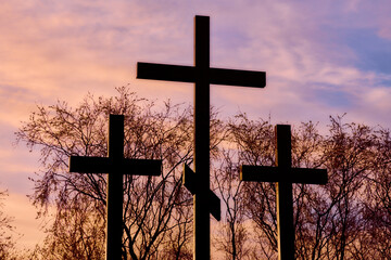 Three crosses in silhouette at sunset, dramatic sky