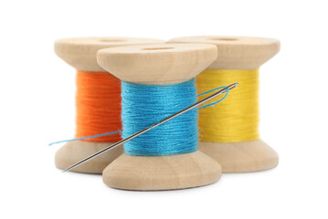 Different colorful sewing threads with needle on white background, closeup