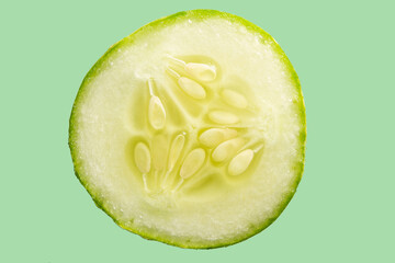 Close em uma fatia de pepino em fundo verde, com espaço para texto.