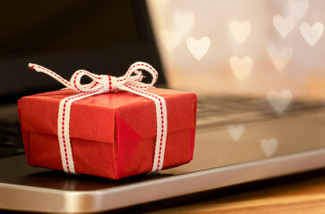 Red gift boxes and heart shaped box with laptop on wooden table. Gift, present and love concept.