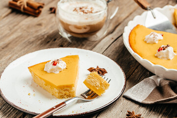 Pumpkin cheesecake, pumpkin pie with whipped cream on the wooden table. Homemade pastry for Thanksgiving