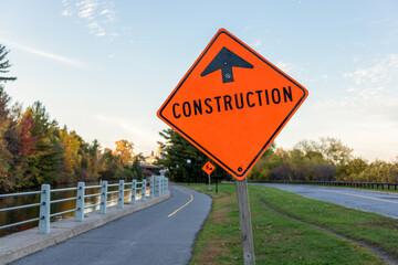 Construction orange sign with arrow closeup on the road along Rideau canal in Ottawa, Canada in the...