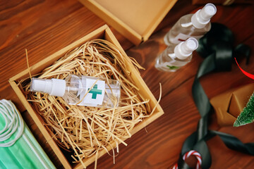Fototapeta na wymiar Top view of box of straw and antiseptic. Gift against coronavirus, sanitizers, medical masks and a satin ribbon on wooden table. Concept of fighting virus and bacteria in quarantine.