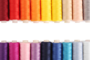Frame of colorful sewing threads on white background, flat lay. Space for text