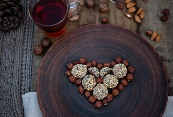 Vegan chocolate truffles like heart on the brown plate with nuts. Top view. Close-up. Copy space. Soft focus. St. Valentines day. Wooden background.