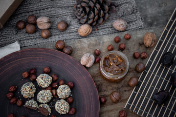 Vegan chocolate truffles on the brown dish with nuts. Top view. Close-up. Copy space. Soft focus. Wooden background.